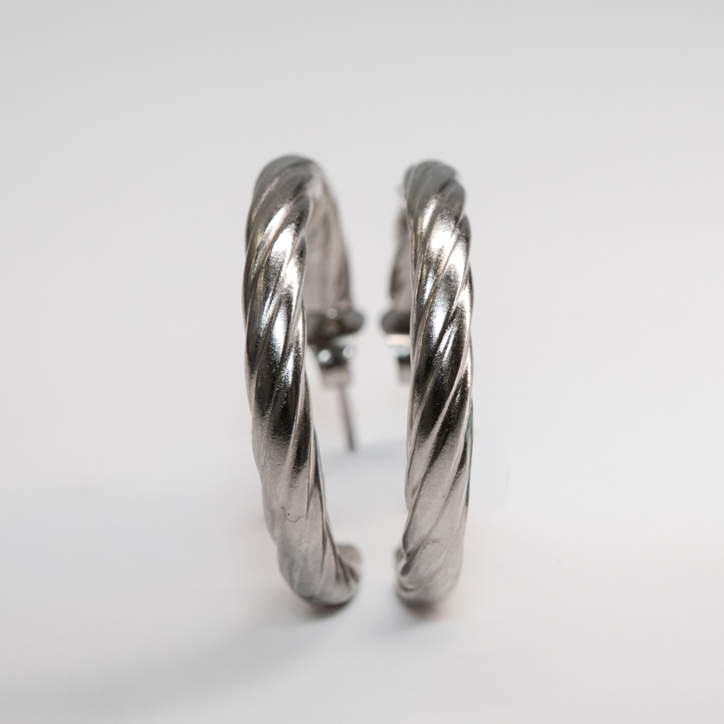 Silver Vera Twist Hoops with smooth reflective texture and graceful curves
