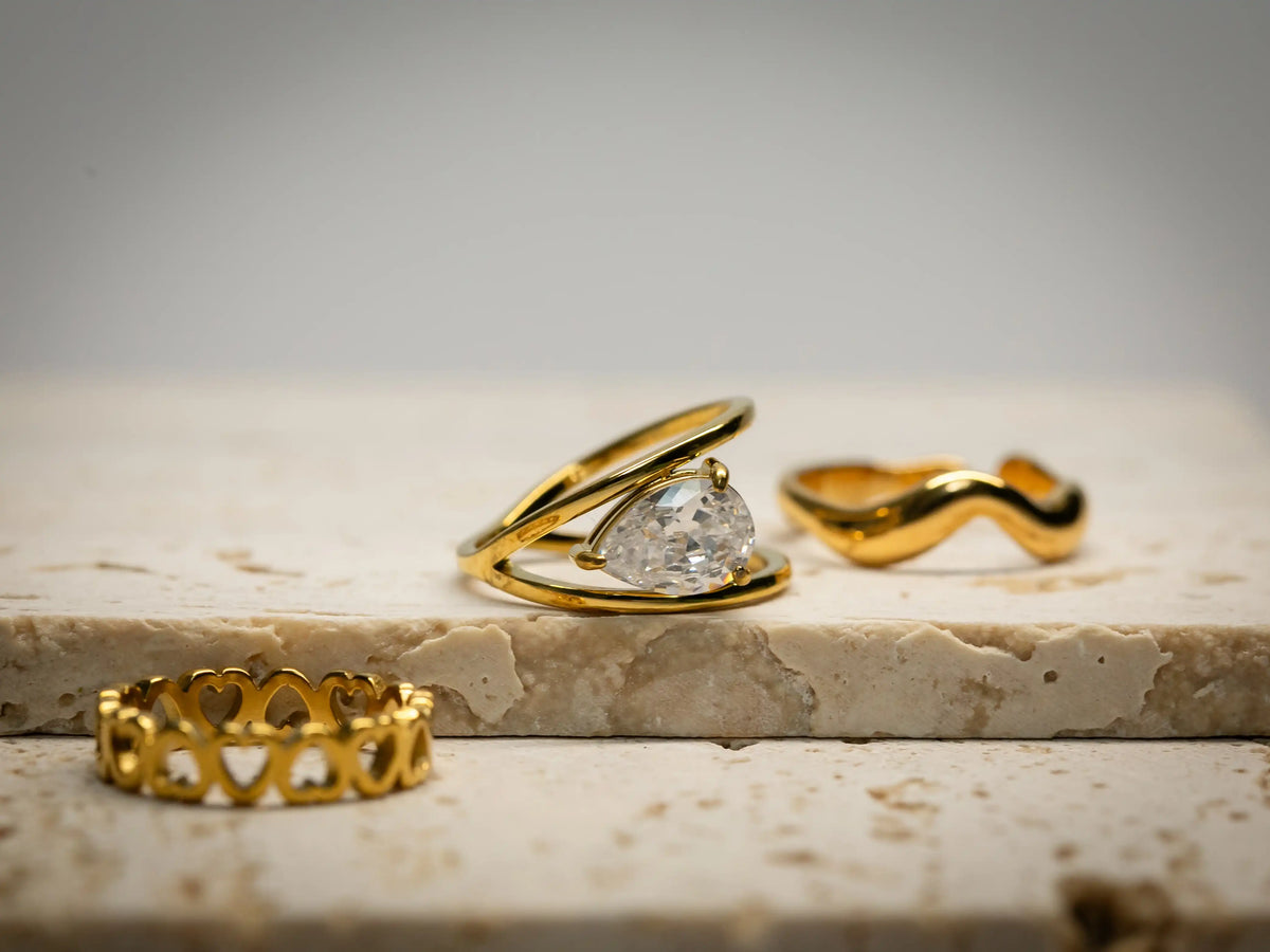 Three gold rings on a marble surface with a neutral background