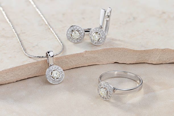 Silver jewelry set with necklace, earrings, and ring on a beige surface